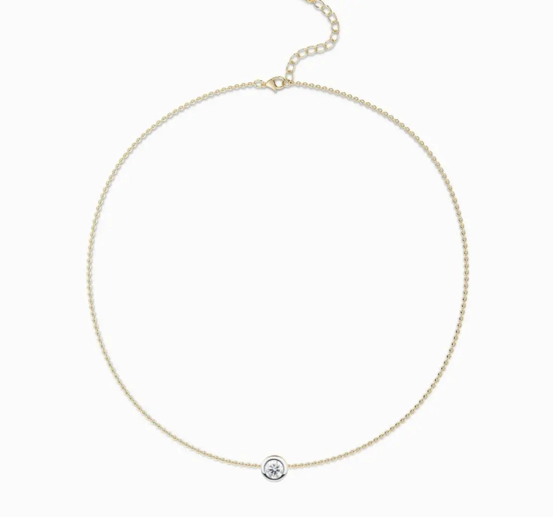 Gold necklace with a small round pendant on a white background